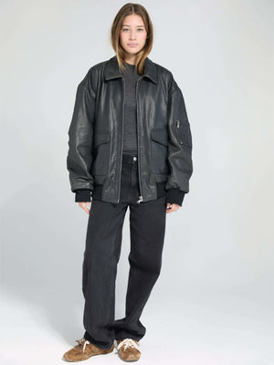 A model wears a stylish oversized black leather jacket paired with black pants, showcasing a modern, casual look by MEOTINE.
