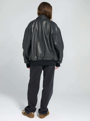 A model wearing a black oversized leather bomber jacket from MEOTINE, paired with dark pants, viewed from the back.