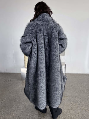 Luxurious gray faux fur coat drapes elegantly on a model, showcasing a cozy and stylish look by MEOTINE.