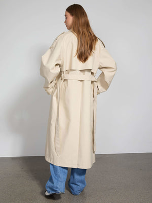 A model showcases a stylish beige trench coat with a belted waist, paired with wide-leg jeans, embodying MEOTINE's chic aesthetic.