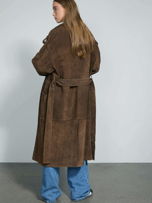 A model showcases a brown suede long coat with a belt, styled with loose blue jeans, embodying a chic, casual look by MEOTINE.