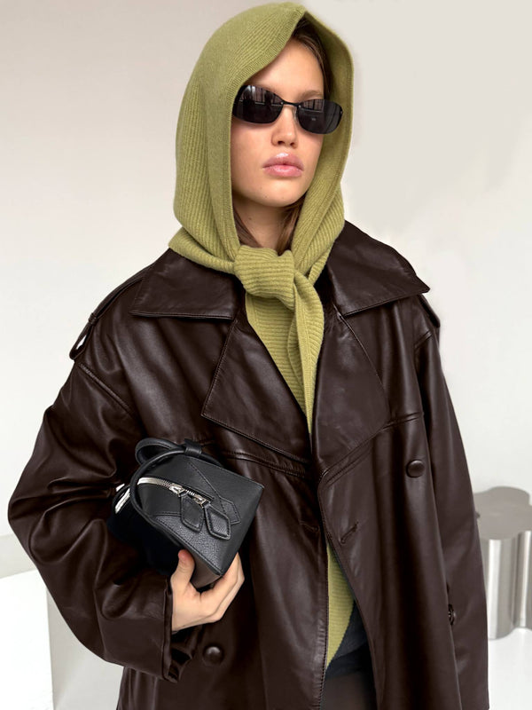 A model wearing a brown oversized leather coat and a green hooded sweater, holding a small black bag, showcasing MEOTINE style.