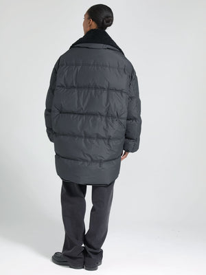 A model wearing a black oversized puffer jacket with a cozy collar, showcasing the stylish design of MEOTINE.