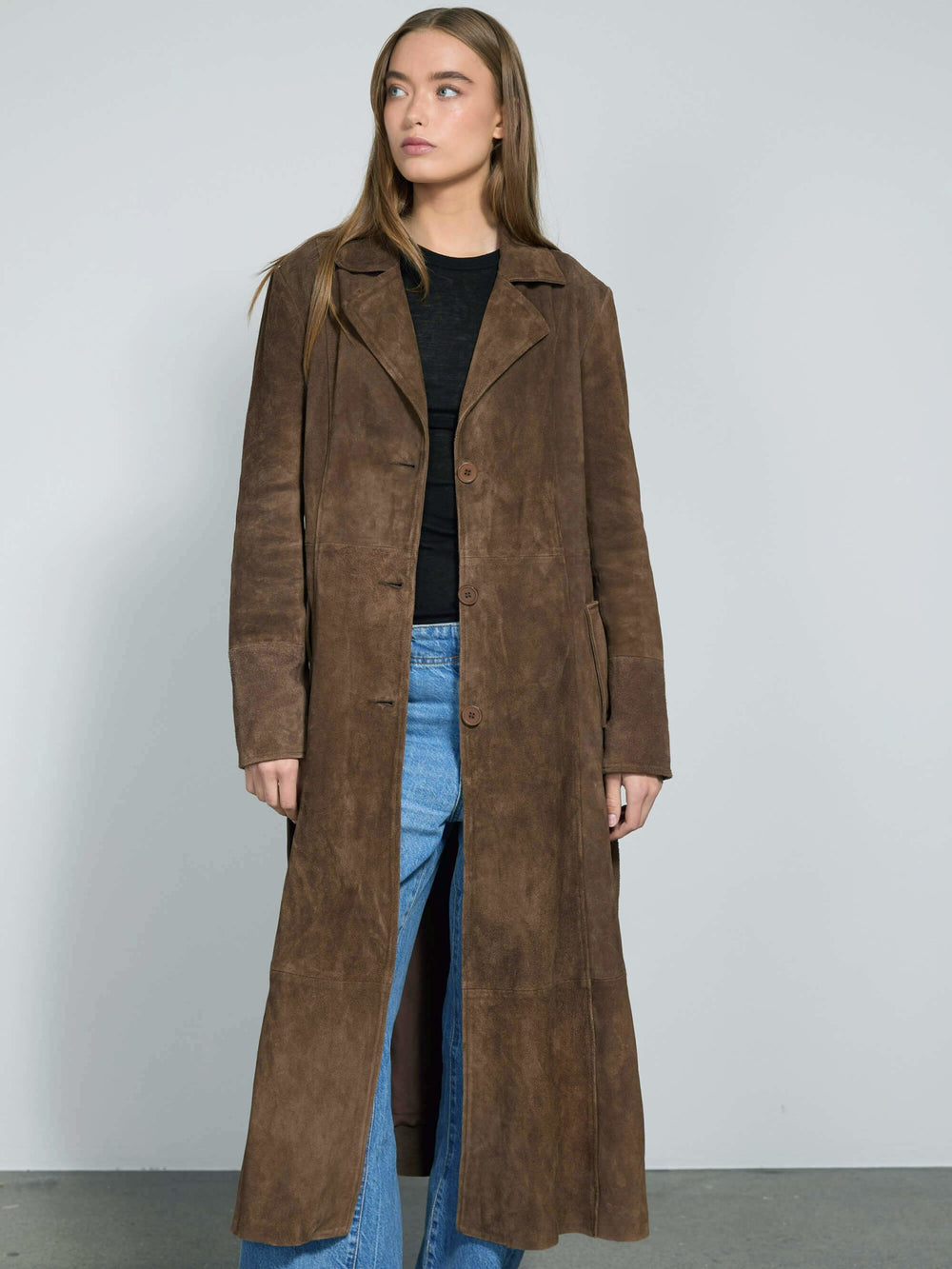 A model wears a long brown suede coat with a belt, paired with wide-leg jeans, showcasing MEOTINE's stylish outerwear.