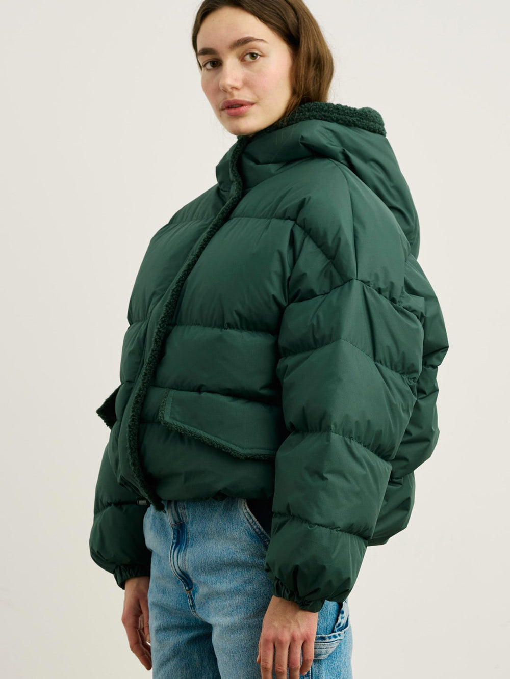 A model wears a stylish green puffer jacket with a cozy collar, paired with light blue jeans, showcasing MEOTINE's trendy design.