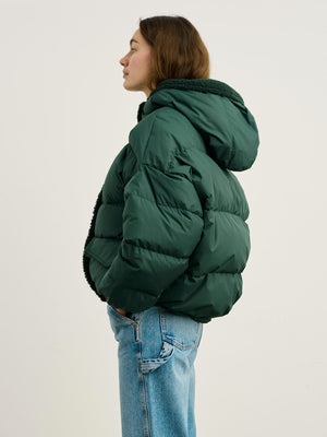 A woman in a green puffer jacket with a cozy hood, styled with light blue jeans, showcasing MEOTINE's trendy winter fashion.