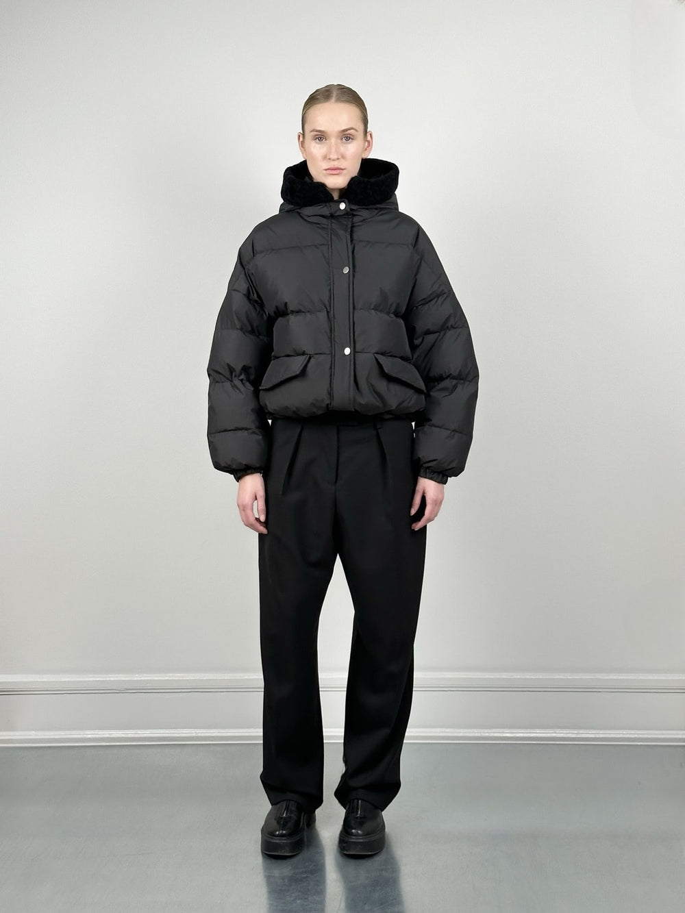Stylish black puffer jacket with a hood, paired with high-waisted black trousers, showcasing MEOTINE's modern winter fashion.