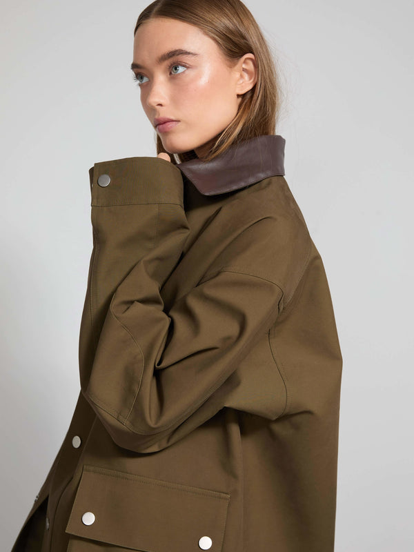 A model showcases a stylish brown MEOTINE jacket with a unique collar, exuding a modern and sophisticated look.