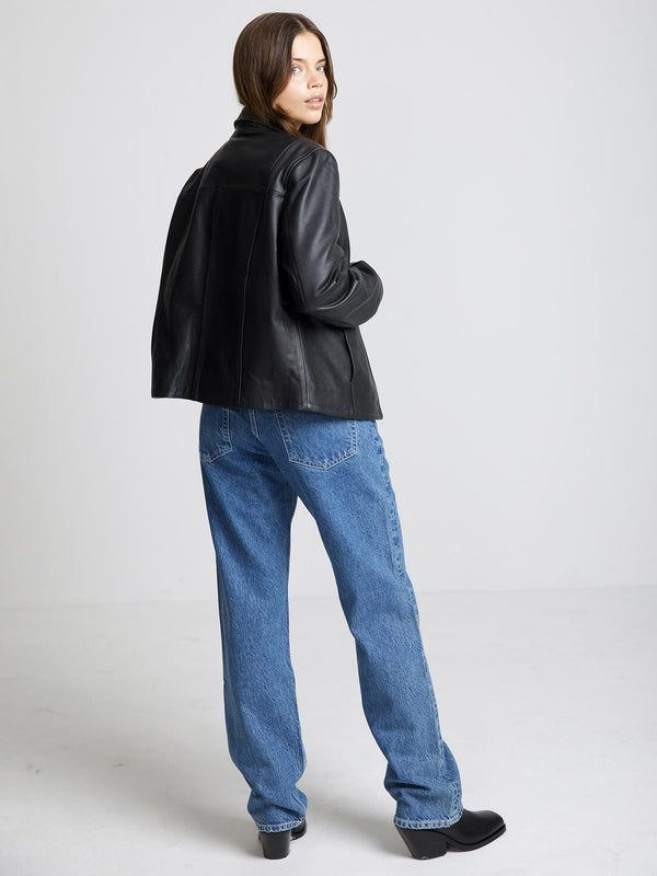 A model showcases a stylish black leather jacket paired with loose blue jeans, embodying a chic, casual look by MEOTINE.