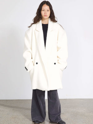 A model wears a cozy white oversized coat with black buttons, paired with dark wide-leg pants, showcasing MEOTINE's stylish design.