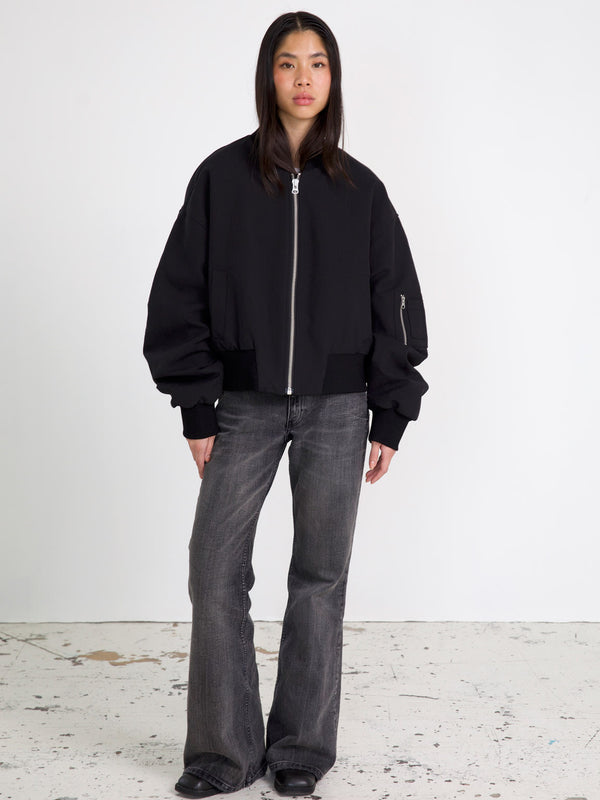 A model wears a stylish black bomber jacket with oversized sleeves, paired with flared jeans, showcasing MEOTINE's modern aesthetic.