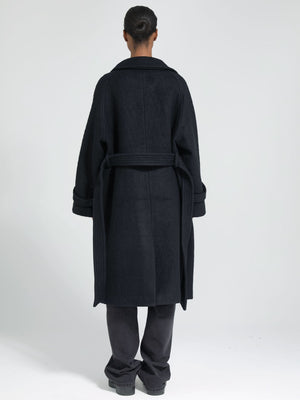 A model wearing a black oversized coat with a belt, showcasing a stylish and cozy design by MEOTINE from the back.