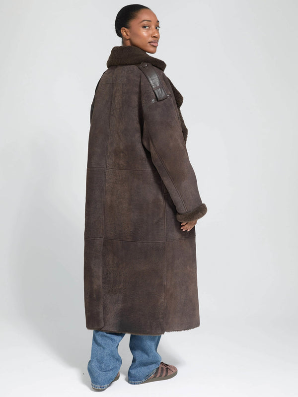 A model showcases a stylish brown shearling coat with a high collar and leather accents, embodying MEOTINE's chic aesthetic.