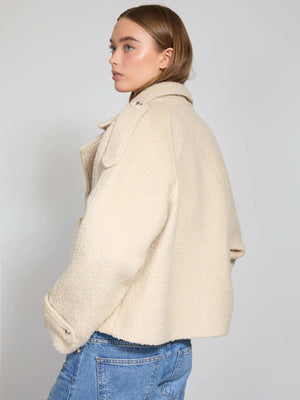 A model showcases a stylish cream-colored MEOTINE jacket, featuring a cozy texture and a relaxed fit, paired with denim jeans.