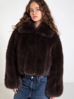 A model showcases a luxurious dark fur jacket with a wide collar, paired with high-waisted jeans, embodying MEOTINE's chic style.