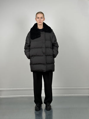 A model wears a stylish black puffer coat with a plush collar, paired with loose black trousers, showcasing MEOTINE's modern design.