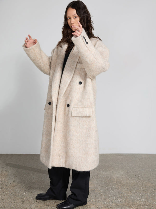 A model showcases a cozy, oversized beige coat with a textured finish, featuring a double-breasted design by MEOTINE.