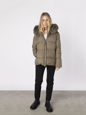 Stylish olive green puffer jacket with a fur-lined hood, perfect for winter, by MEOTINE. Model wears it with black pants.