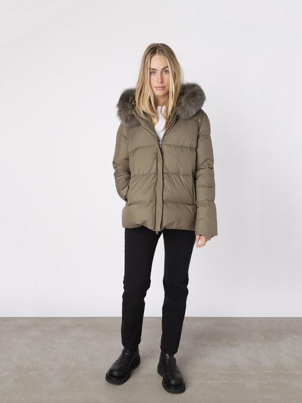 Stylish olive green puffer jacket with a fur-lined hood, perfect for winter, by MEOTINE. Model wears it with black pants.