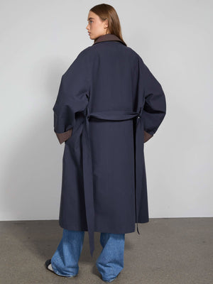 A model showcases a stylish navy trench coat with a belted waist, paired with wide-leg jeans, embodying MEOTINE's modern elegance.