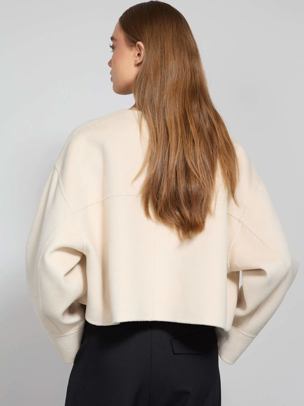 A model showcases a cozy, cream-colored cropped sweater with a relaxed fit, perfect for layering. MEOTINE offers stylish comfort.
