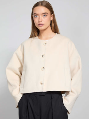 A model wears a cream-colored cropped jacket with large buttons and side pockets, showcasing MEOTINE's stylish design.