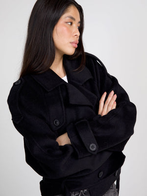 A model poses in a stylish black MEOTINE jacket, showcasing its oversized fit and unique button details against a neutral background.