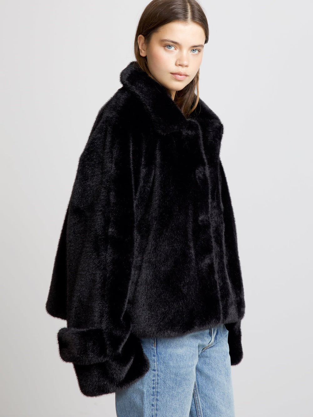 A model showcases a luxurious black faux fur coat by MEOTINE, featuring a wide collar and oversized sleeves, paired with denim.