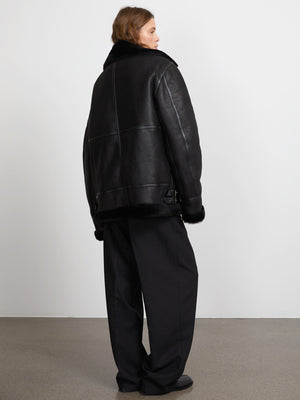 A model showcases a black leather jacket with fur trim, paired with loose black trousers, embodying MEOTINE's chic style.