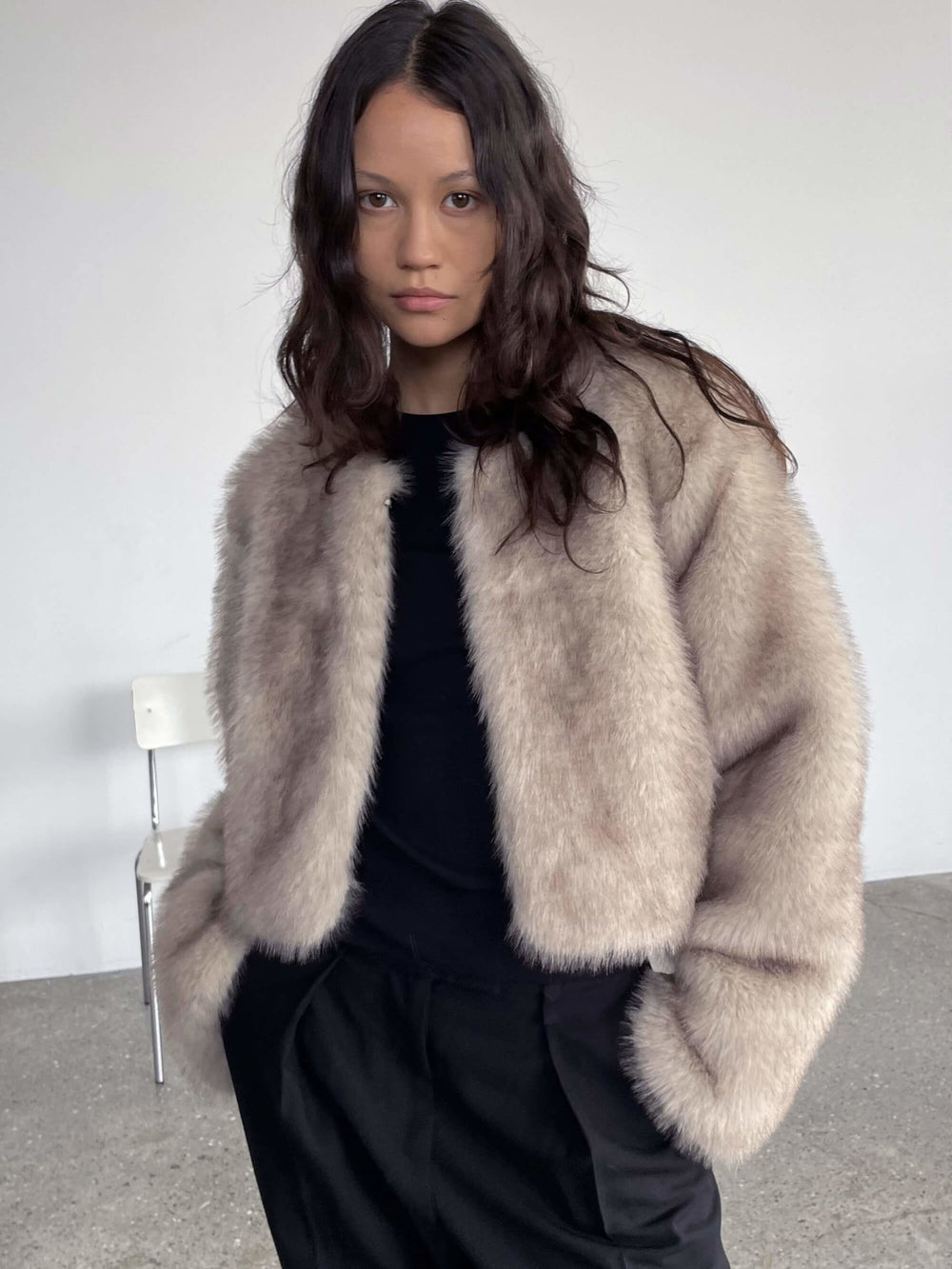 A model wearing a soft, beige faux fur jacket by MEOTINE, styled with black pants, exuding a cozy and chic vibe.