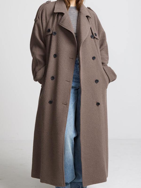 A stylish long brown coat with a relaxed fit, featuring a double-breasted design and large buttons, perfect for layering by MEOTINE.