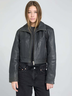 A model wearing a cropped black leather jacket from MEOTINE, paired with high-waisted black jeans, set against a light background.