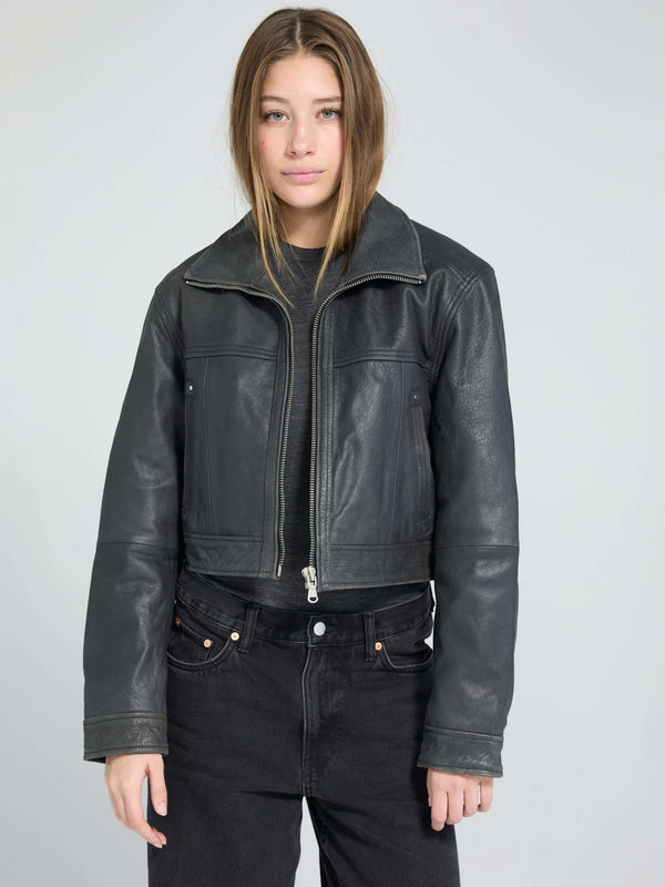 A model wearing a cropped black leather jacket from MEOTINE, paired with high-waisted black jeans, set against a light background.
