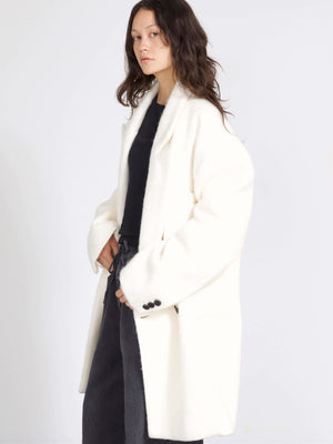 A model showcases a cozy white oversized coat by MEOTINE, paired with a black top and relaxed gray pants, exuding effortless style.