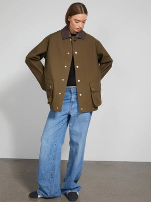 A model wears a stylish olive green MEOTINE jacket with a brown collar, paired with wide-leg jeans for a trendy look.