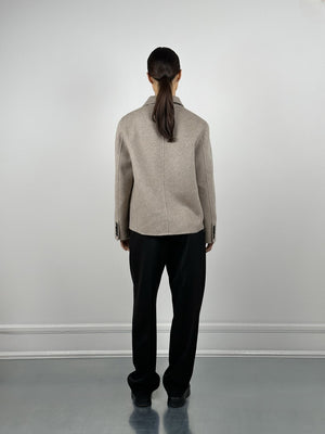 A model wearing a beige oversized blazer from MEOTINE, paired with black trousers, stands against a minimalist backdrop.