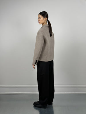 A model showcases a stylish MEOTINE jacket from the back, paired with loose black trousers and sleek black boots.