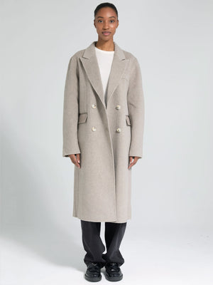 A model showcases a stylish beige double-breasted coat by MEOTINE, paired with a simple white top and black pants.