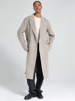 A model showcases a stylish beige double-breasted coat by MEOTINE, paired with a simple white top and black trousers.