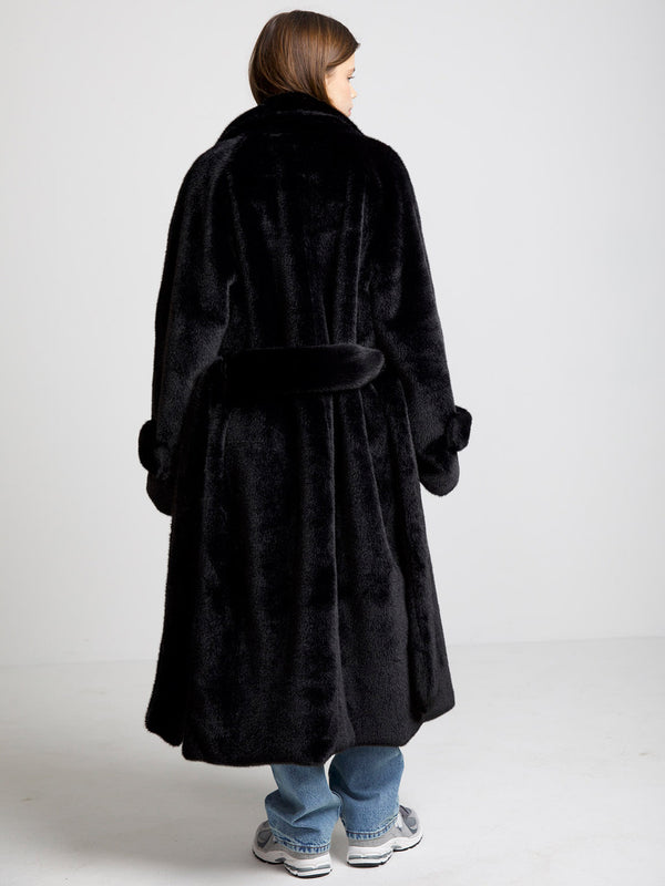 A model wearing a luxurious black faux fur coat by MEOTINE, showcasing a stylish and cozy design from the back.