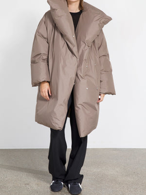 Oversized taupe puffer coat with a dramatic collar, styled with black pants and shoes, showcasing MEOTINE's modern design.