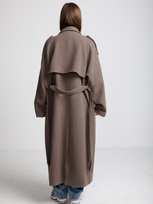 A model wearing a long, brown MEOTINE coat with a belted waist, showcasing a stylish back view against a neutral background.