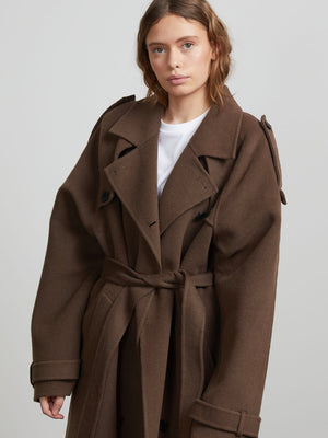A model showcases a stylish brown oversized trench coat with a belt, featuring a classic collar and button details, by MEOTINE.