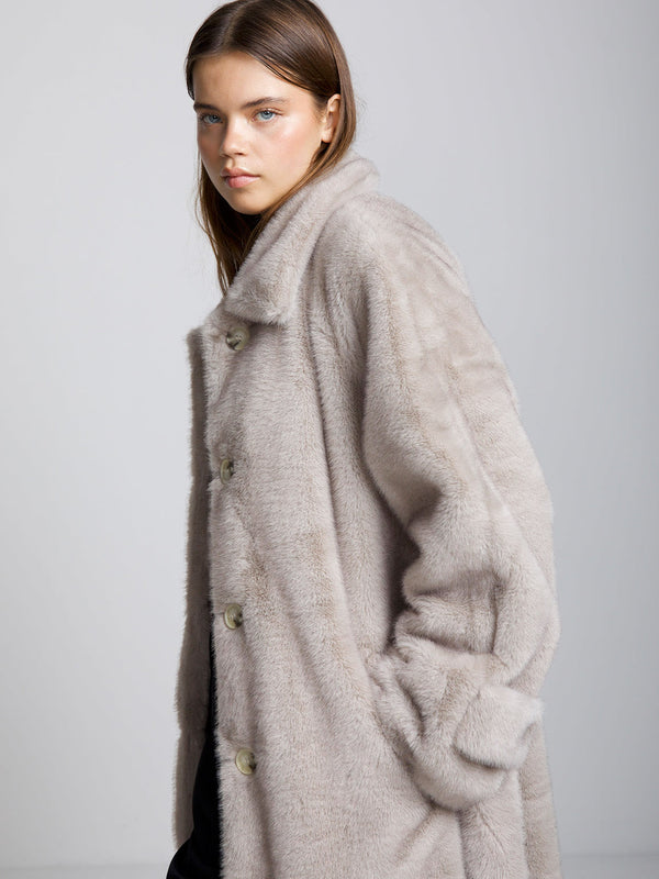 A model wearing a soft, oversized beige coat with a relaxed fit and large buttons, showcasing MEOTINE's cozy style.