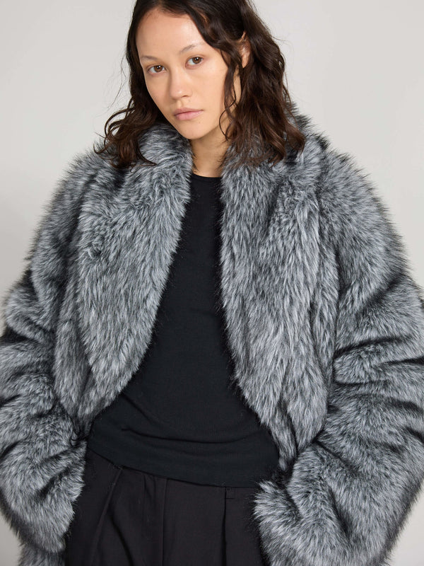 A model showcases a luxurious gray faux fur coat by MEOTINE, featuring a cozy, oversized design and a stylish collar.