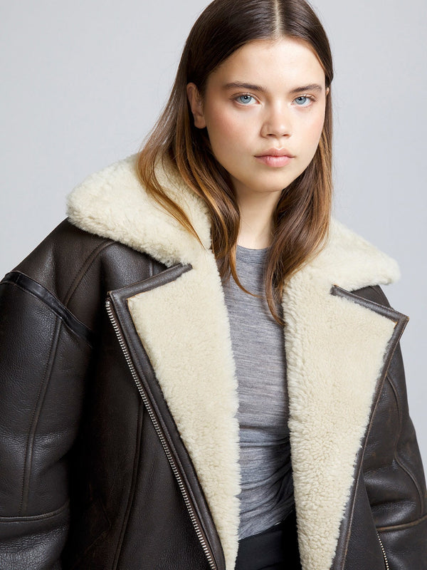 A model showcases a stylish brown leather jacket with a cozy cream shearling collar, embodying MEOTINE's chic aesthetic.