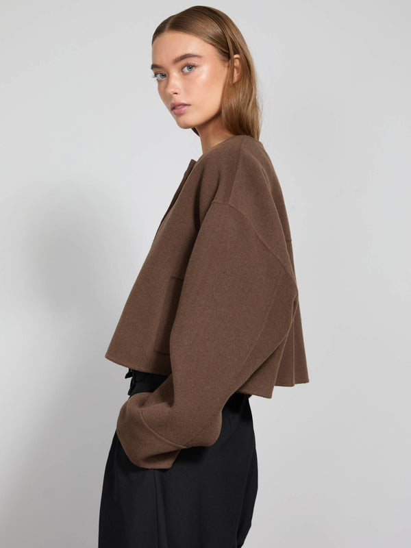 A model showcases a brown cropped sweater with a relaxed fit, paired with black trousers, embodying MEOTINE's chic style.
