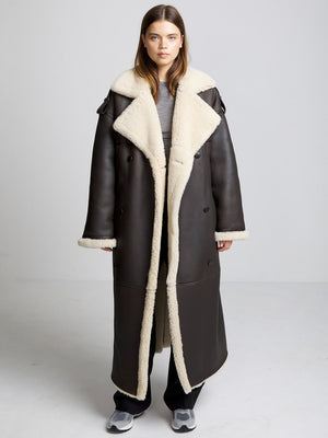 A model showcases a stylish brown shearling coat with a cozy cream lining, perfect for a chic winter look by MEOTINE.