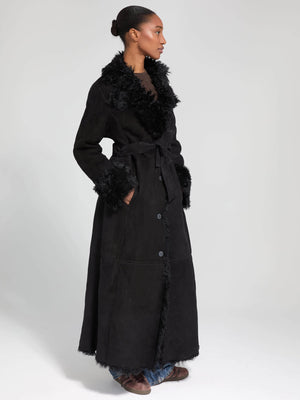 A stylish black long coat with a fur collar and cuffs, featuring a belted waist and side pockets, by MEOTINE.