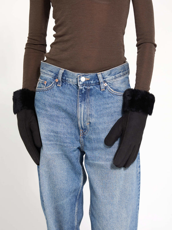 Stylish black gloves with faux fur cuffs, perfect for winter, showcased on a model wearing high-waisted jeans. MEOTINE brand.